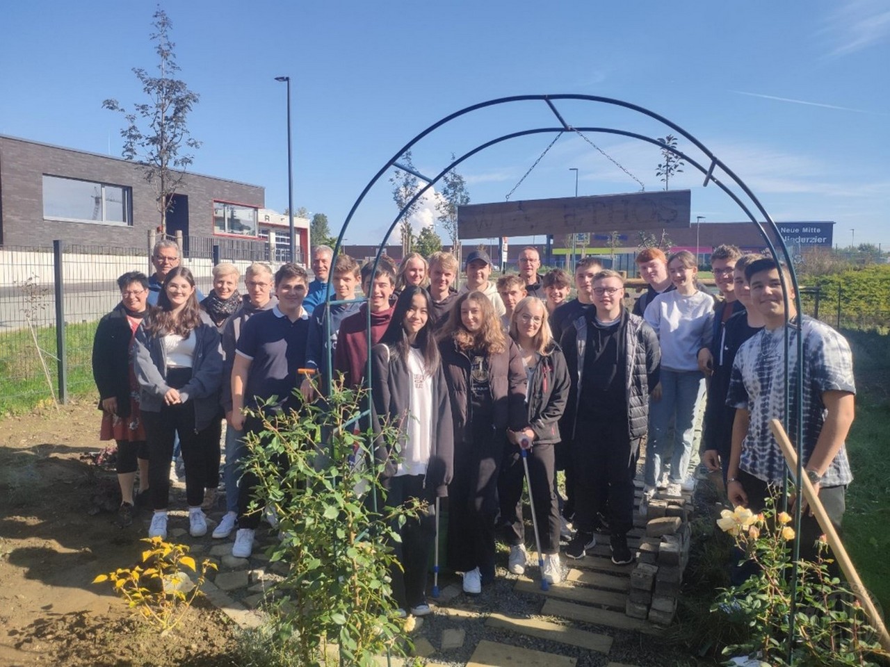 Eine weiße Rose am Eingang des Gartens war schon im vorherigen Jahr gepflanzt worden. Der Grundstein für diesen Garten wurde im Jahr 2019 gelegt, die Idee dazu war im dritten Vernetzungstreffen der beiden Schulen aus Taucha und Niederzier im Jahr 2018 entstanden. Schülerinnen und Schüler haben den Garten angelegt, jetzt fehlen nur noch die Sitzgelegenheiten. c Weiße Rose