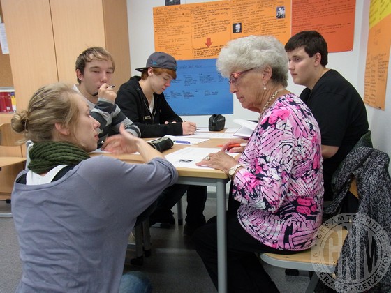 Eine Studentin erläutert Frau Falk und den Schülern Fragen.