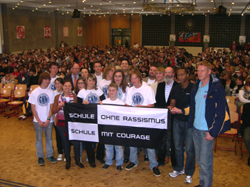 Die Schülervertretung, der Schulleiter der Gesamtschule Niederzier/Merzenich und die Paten von evivo Düren präsentieren stolz das Banner, das der Schule den Titel 'Schule ohne Rassismus - Schule mit Courage' verleiht.  